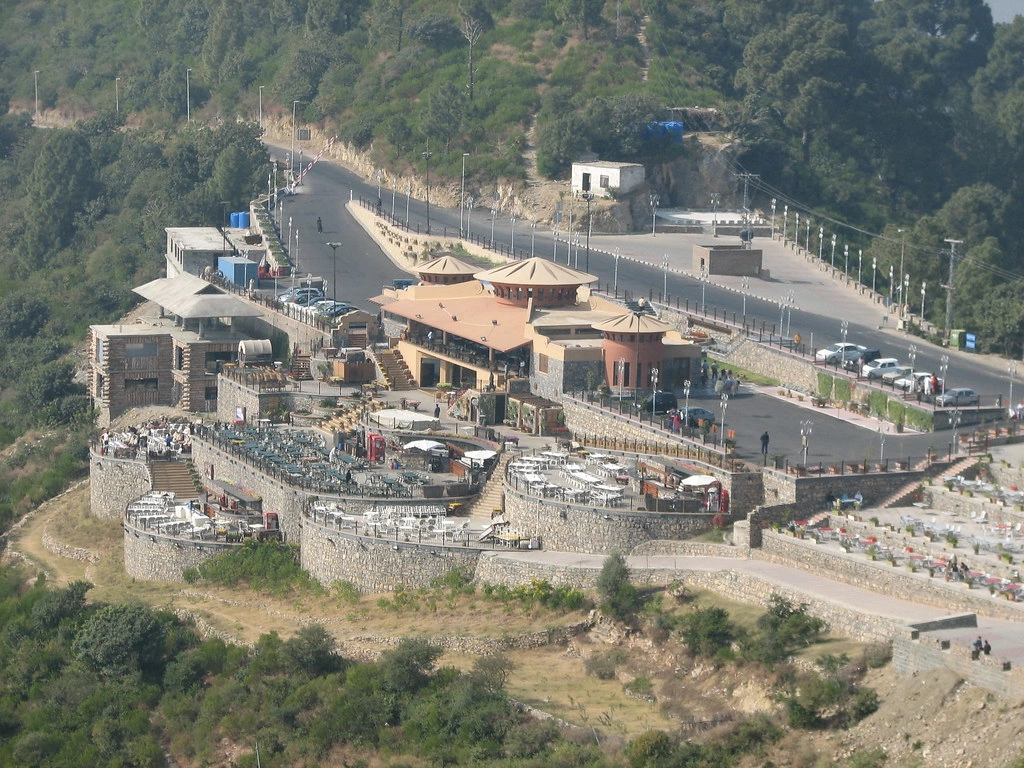 Aerial view of Monal Restaurant in Islamabad at Pir Sohawa, surrounded by lush hills and terraces, a popular tourist spot for travelers in 2026.